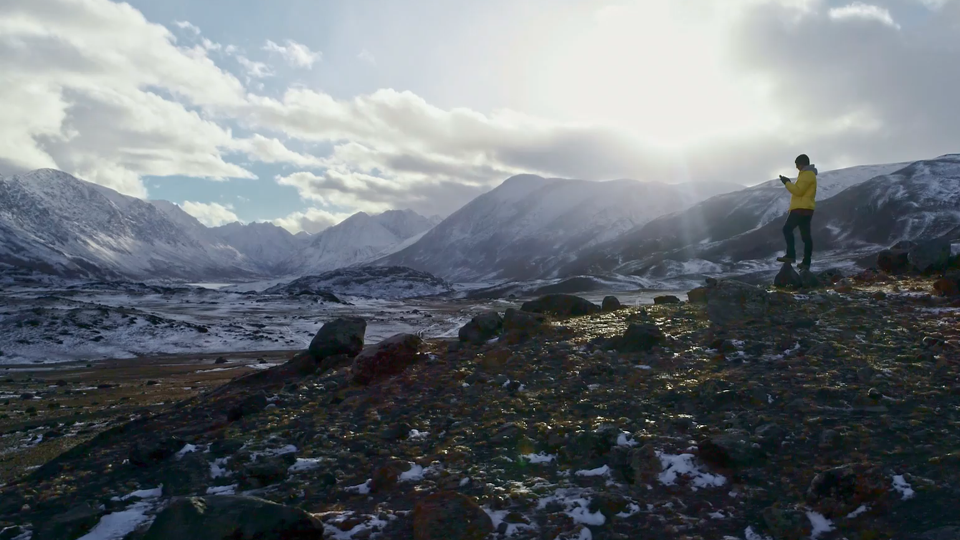 Person hiking in snowy mountain landscape at sunrise.