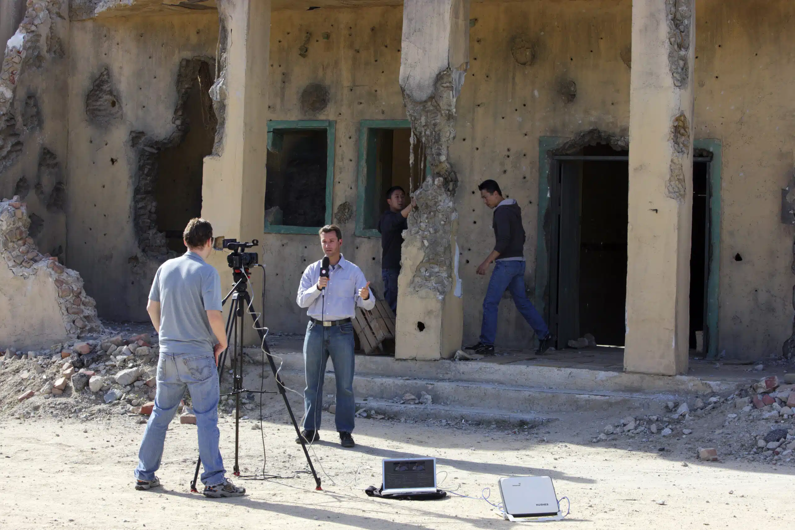 Reporter filming outside damaged building