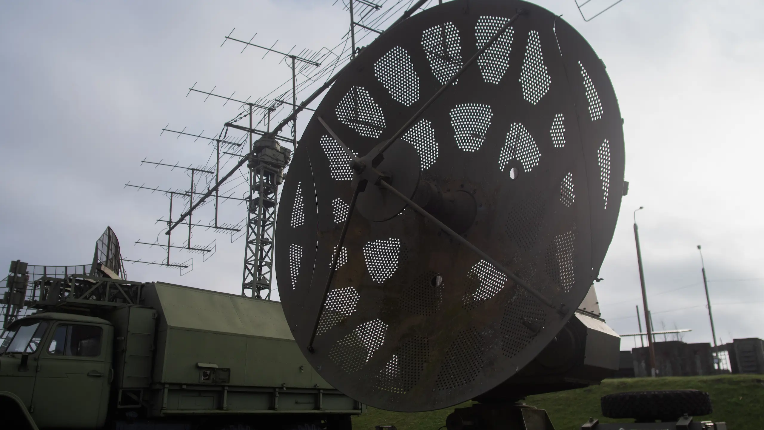 Military radar truck with large satellite dish.