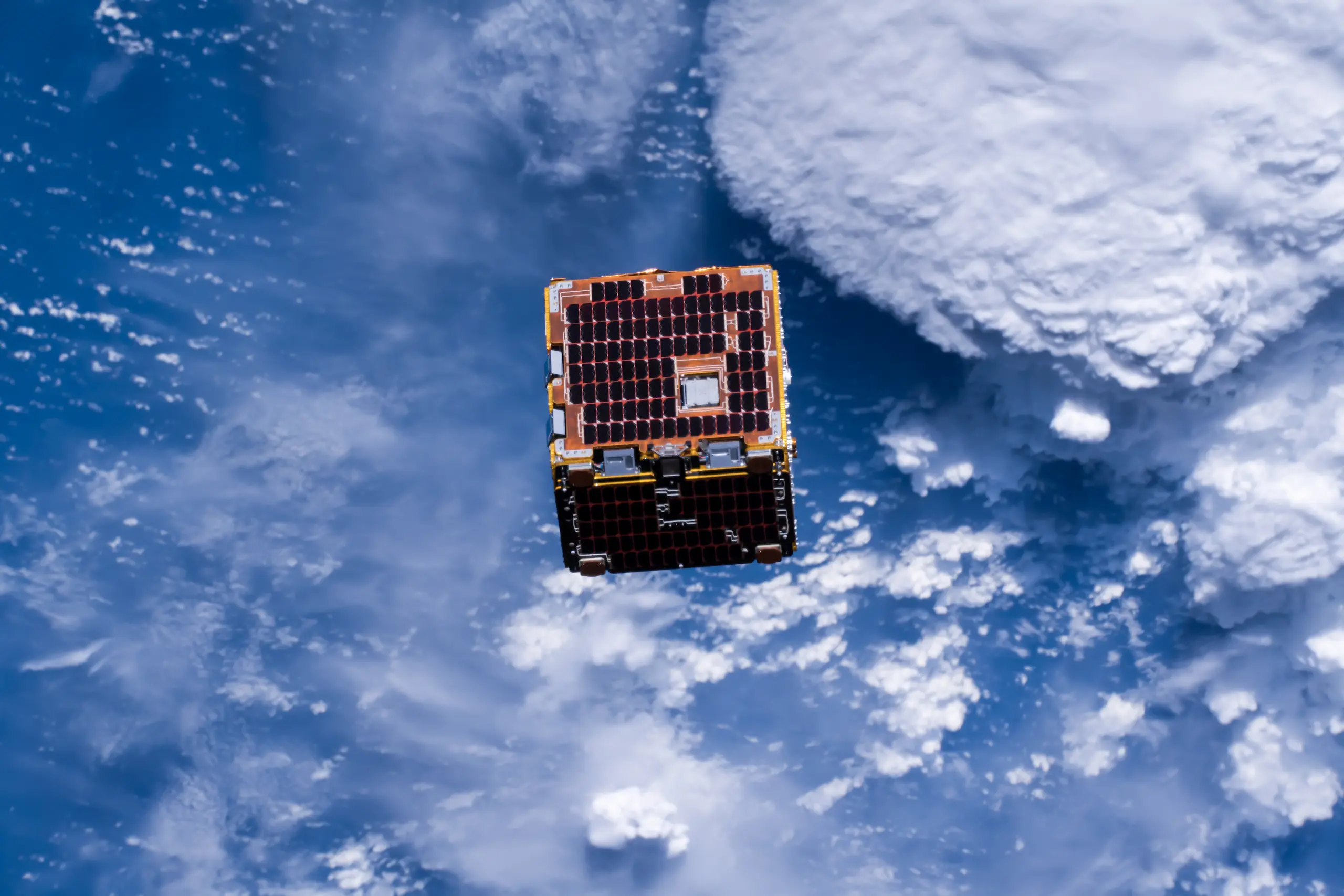 Cube satellite orbiting Earth, atmosphere visible.